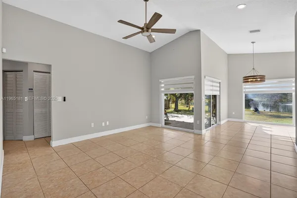 a view of an empty room with a fireplace and a chandelier fan