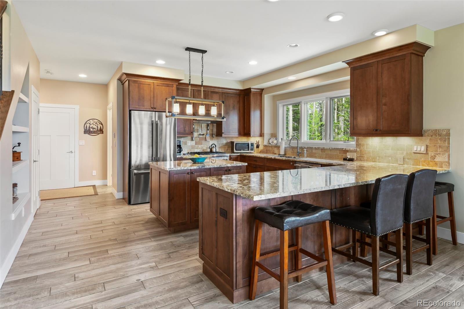 1555 Three Peaks Road Black Hawk, CO 80422 - Photo 22 of 50 a kitchen with stainless steel appliances granite countertop wooden floor a refrigerator a sink and a stove