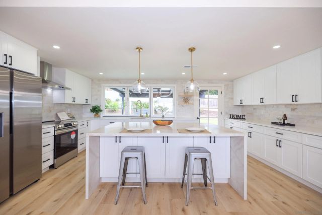 a kitchen with stainless steel appliances kitchen island granite countertop a table chairs and a wooden floor