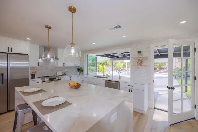 a kitchen with stainless steel appliances granite countertop a dining table chairs and a chandelier