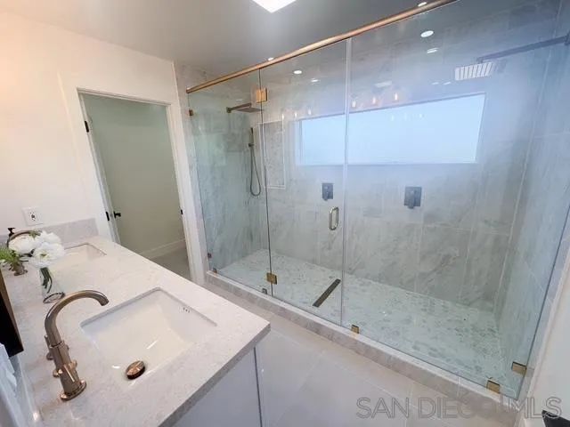 a bathroom with a double vanity sink mirror and shower