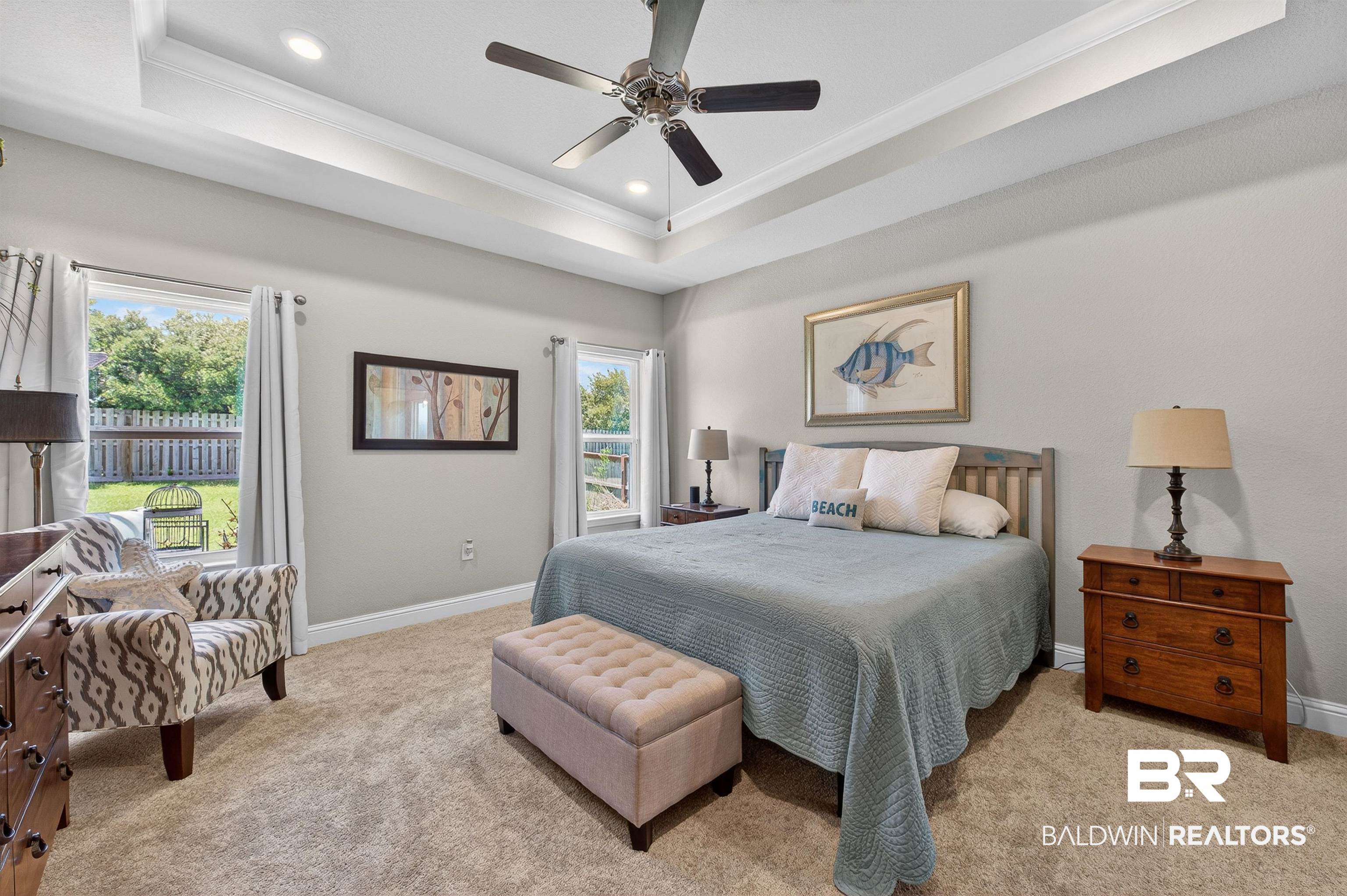 8735 Bronze Lane Foley, AL 36535 - Photo 20 of 58 Spacious bedroom featuring a tray ceiling with recessed lighting, ceiling fan, carpeted flooring, and multiple windows overlooking the fenced backyard