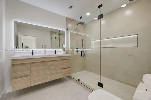 a bathroom with a shower sink mirror and toilet