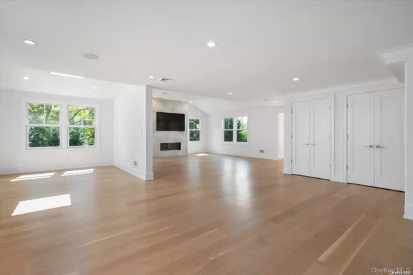 a view of an empty room with a window and wooden floor