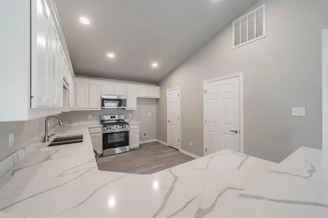 a large white kitchen with kitchen island a sink stainless steel appliances and cabinets