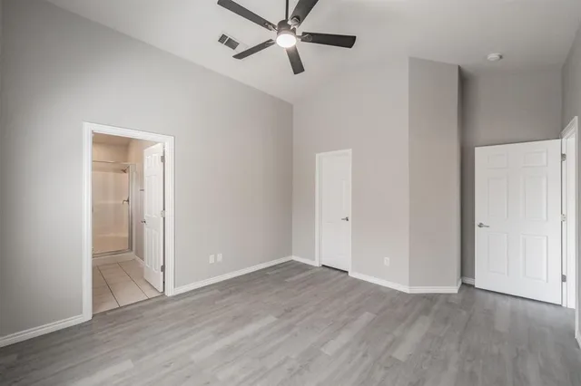 an empty room with wooden floor closet and ceiling fan