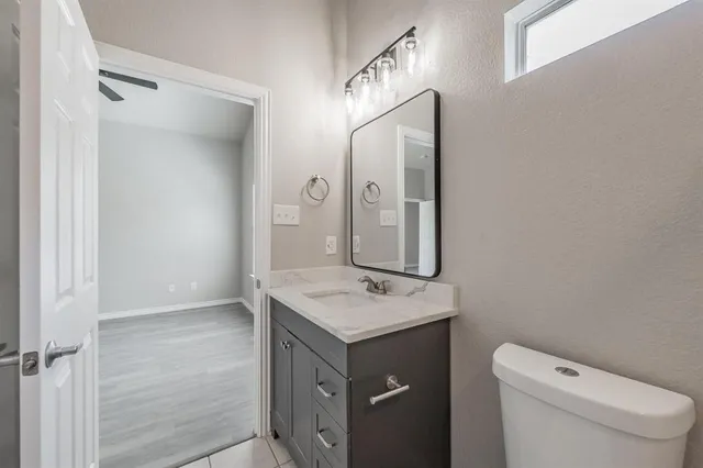 a bathroom with a granite countertop sink mirror vanity and toilet