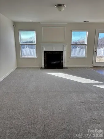 an empty room with windows and fireplace
