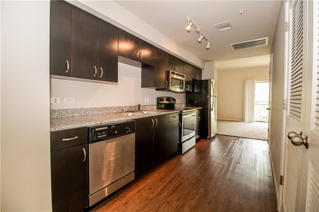1401 East 4th Street, Unit 207 Austin, TX 78702 - Photo 3 of 9 a kitchen with stainless steel appliances granite countertop a stove a sink and a refrigerator