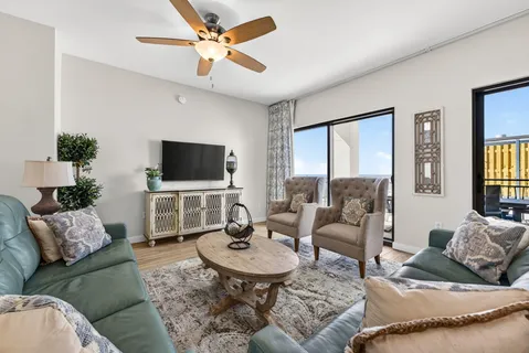a living room with furniture a flat screen tv and a large window