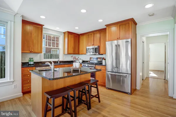 a kitchen with stainless steel appliances granite countertop a refrigerator a sink dishwasher a stove and a refrigerator with wooden floor