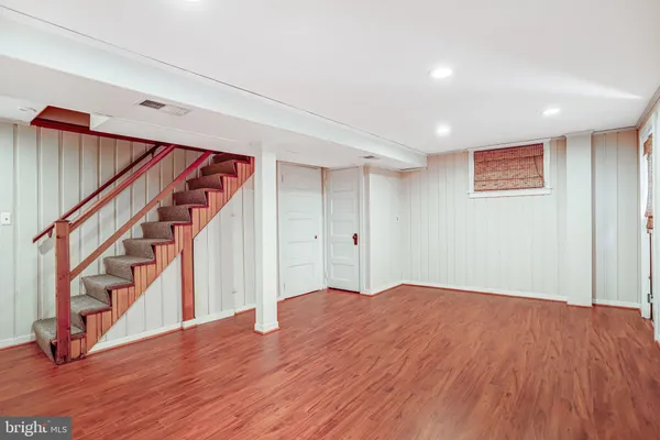 a view of an empty room with wooden floor and stairs