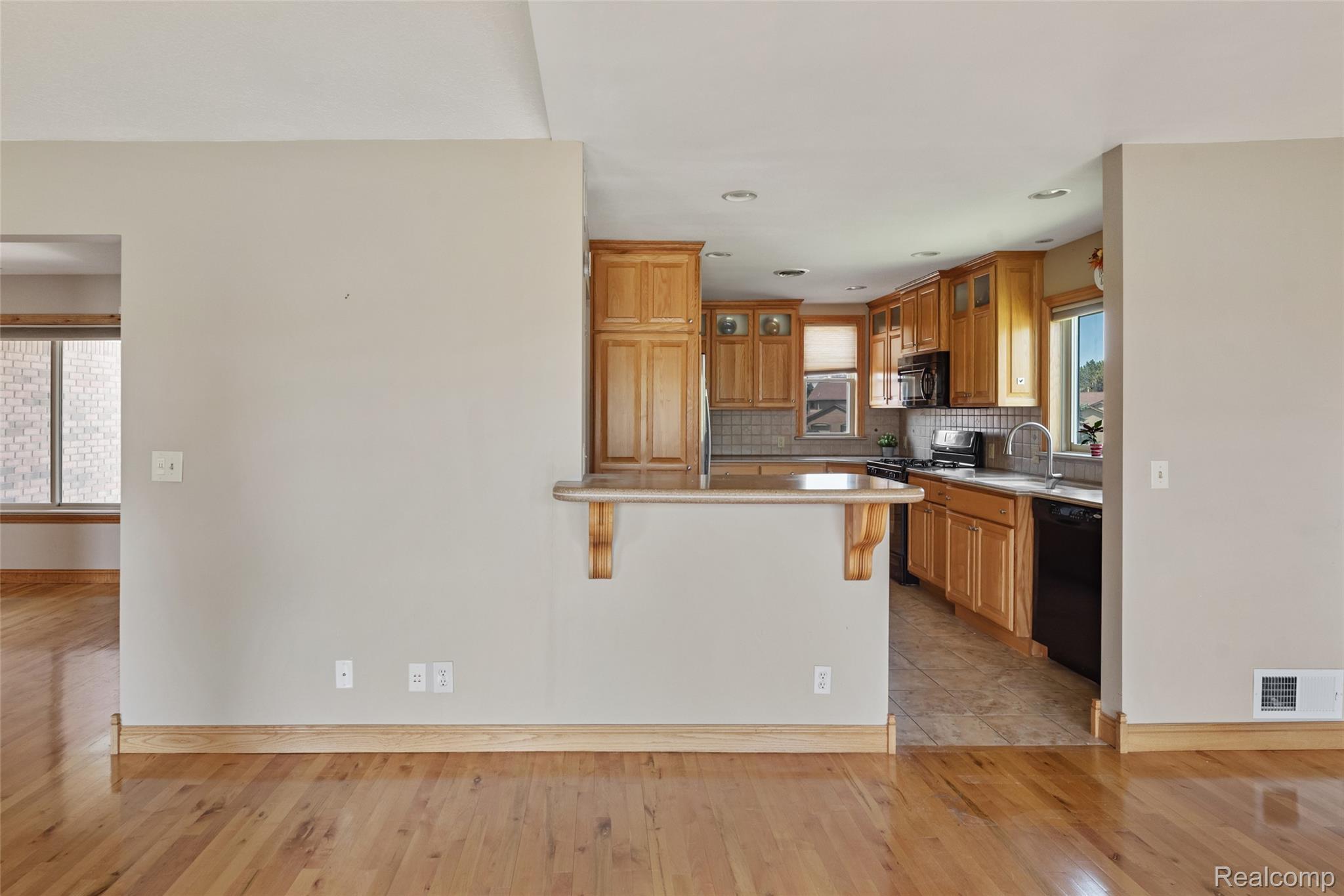 700 Tennyson Rochester, MI 48307 - Photo 11 of 32 Kitchen with a breakfast bar area, light wood-style floors, a peninsula, glass fronted cabinets, and black appliances