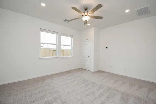 an empty room with windows and ceiling fan