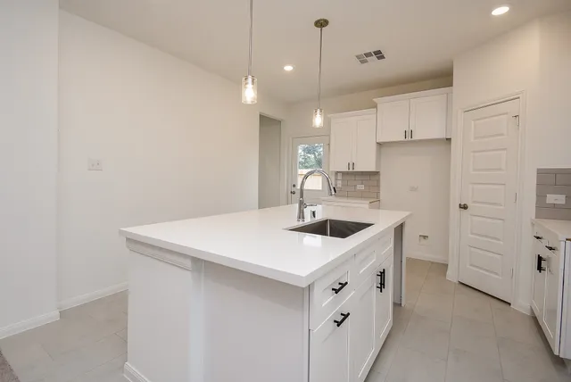 a kitchen with a sink a stove a refrigerator and white cabinets