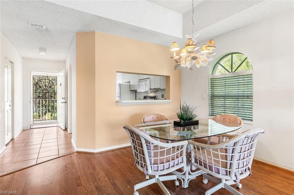 555 Augusta Boulevard, Unit 36 Naples, FL 34113 - Photo 3 of 25 a dining room with furniture a chandelier and wooden floor