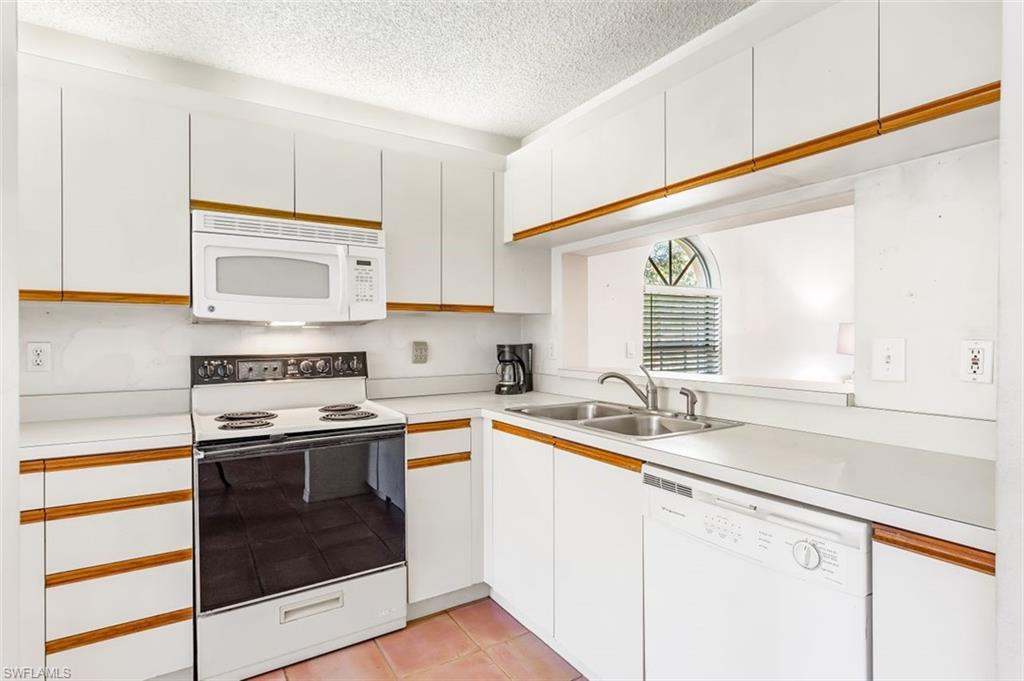555 Augusta Boulevard, Unit 36 Naples, FL 34113 - Photo 7 of 25 a kitchen with a sink stove and cabinets