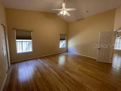 a view of empty room with wooden floor and fan