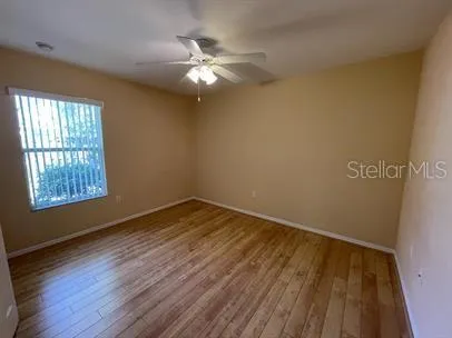 a view of an empty room with wooden floor and a window