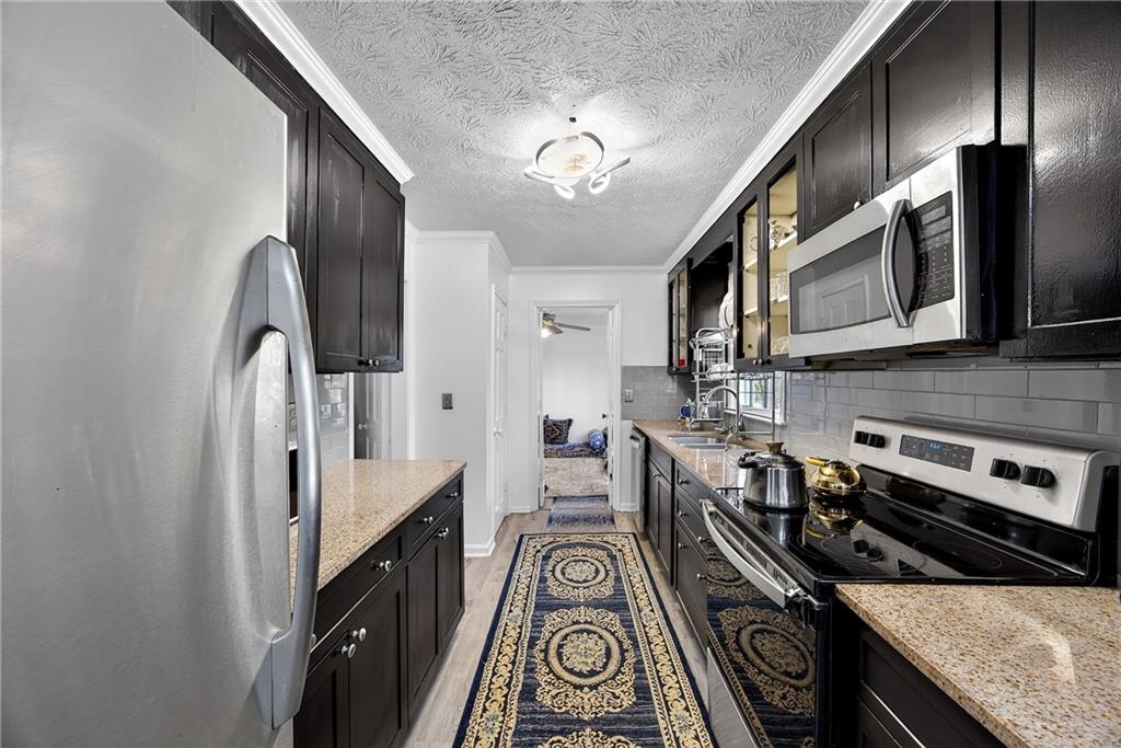 4673 Arrowhead Trail Southwest Lilburn, GA 30047 - Photo 6 of 28 a kitchen with stainless steel appliances granite countertop hardwood floor sink stove and refrigerator