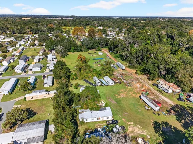 an aerial view of residential houses with outdoor space and trees