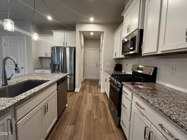 a kitchen with stainless steel appliances granite countertop a stove a sink and a refrigerator