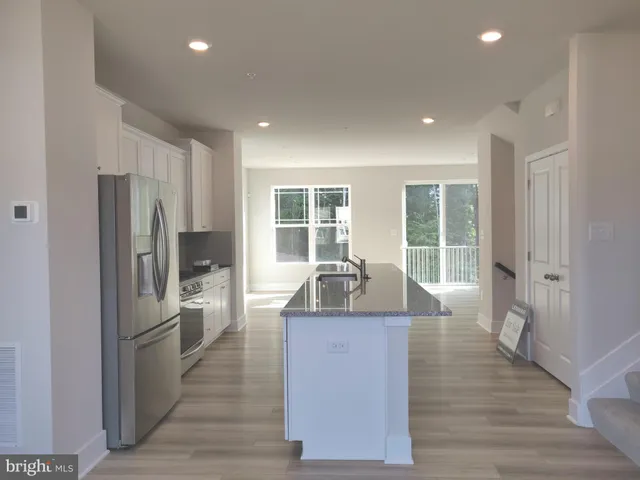 a kitchen with granite countertop a refrigerator sink and white cabinets