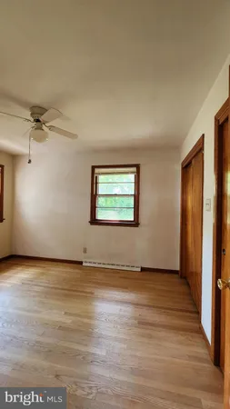 an empty room with wooden floor cabinet and windows