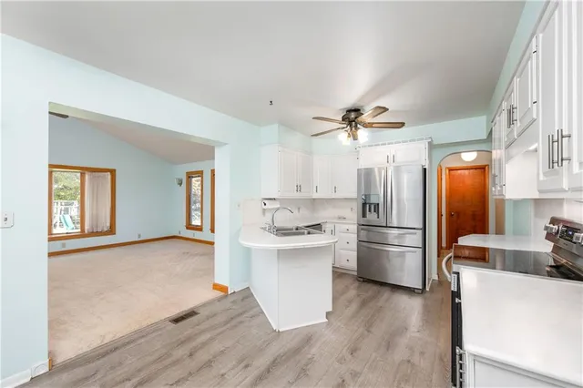 a kitchen with stainless steel appliances a refrigerator a sink dishwasher and a stove with wooden floor