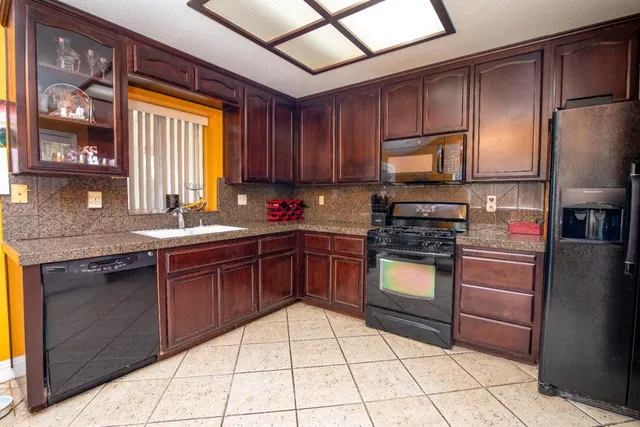 a kitchen with stainless steel appliances granite countertop wooden cabinets a stove top oven a sink and dishwasher