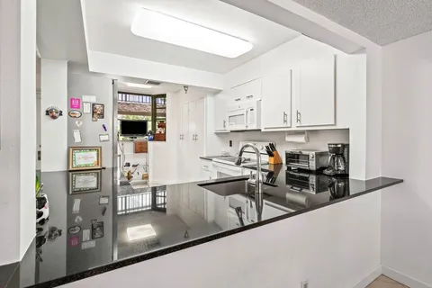 a kitchen with stainless steel appliances granite countertop a sink and a refrigerator