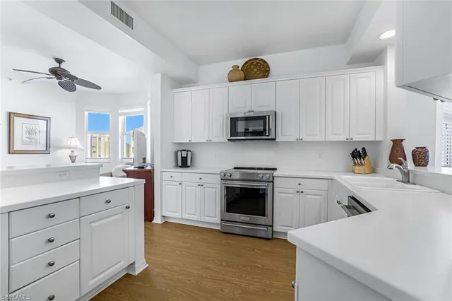 a kitchen with cabinets stainless steel appliances a sink and a stove