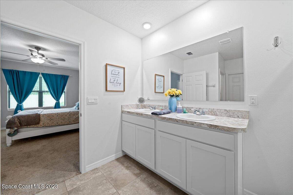 2103 Capital Drive Palm Bay, FL 32909 - Photo 22 of 84 a en suite bathroom with a double vanity sink a mirror and a bathtub