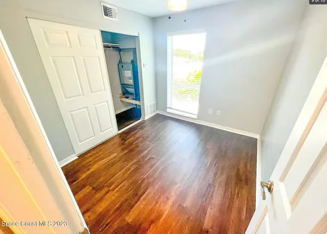 a view of an empty room with wooden floor and a window