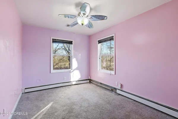an empty room with windows and fan