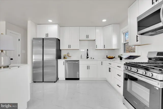 a kitchen with white cabinets and stainless steel appliances
