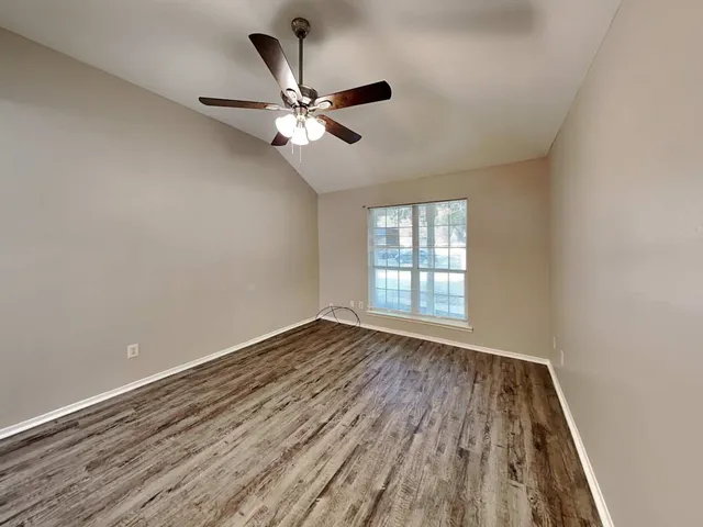 a view of an empty room with wooden floor and window