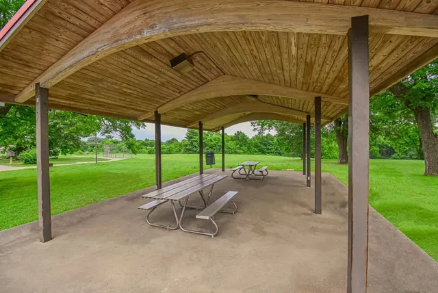 a view of a backyard with table and chairs under a large tree