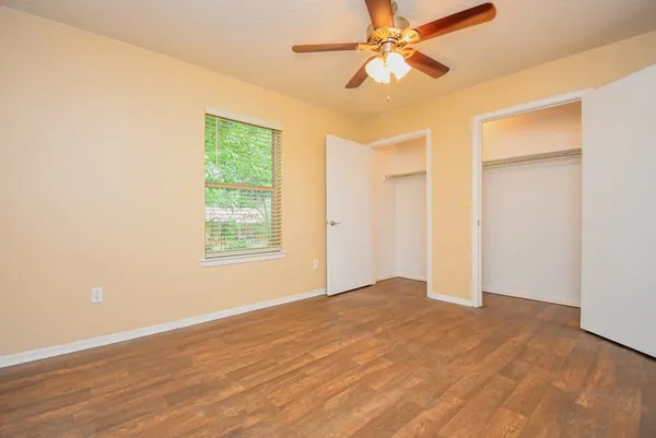 a view of an empty room with window and a chandelier fan