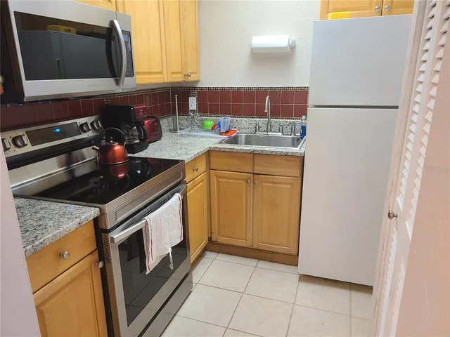 a kitchen with stainless steel appliances granite countertop a refrigerator stove a sink dishwasher and microwave oven