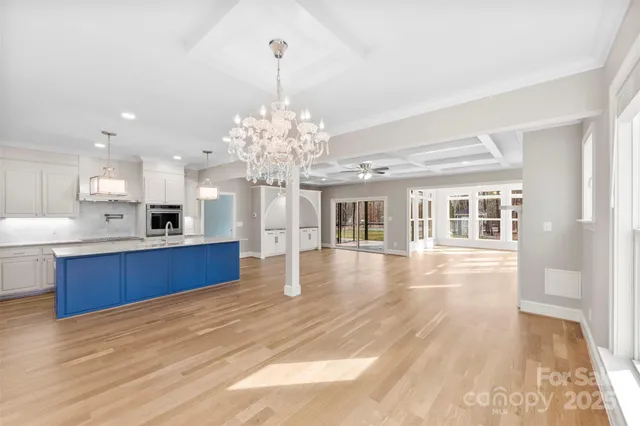 a view of a kitchen with kitchen island a sink wooden floor and a large window