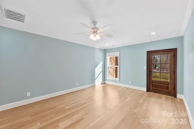 a view of an empty room with a window and wooden floor