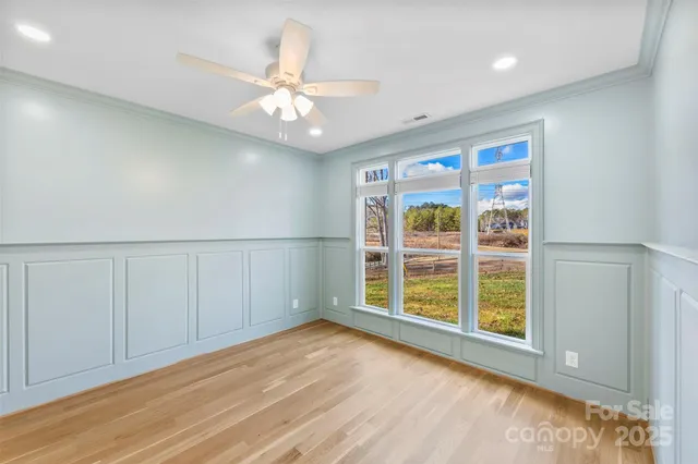 an empty room with wooden floor fan and windows