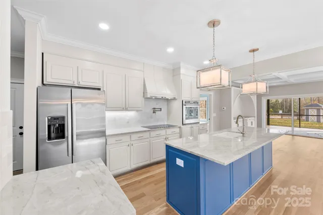 a large kitchen with kitchen island a large counter top space a sink stainless steel appliances and cabinets