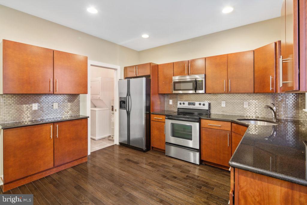2614 Webster Street, Unit A Philadelphia, PA 19146 - Photo 2 of 12 a kitchen with granite countertop wooden cabinets a refrigerator and a stove top oven