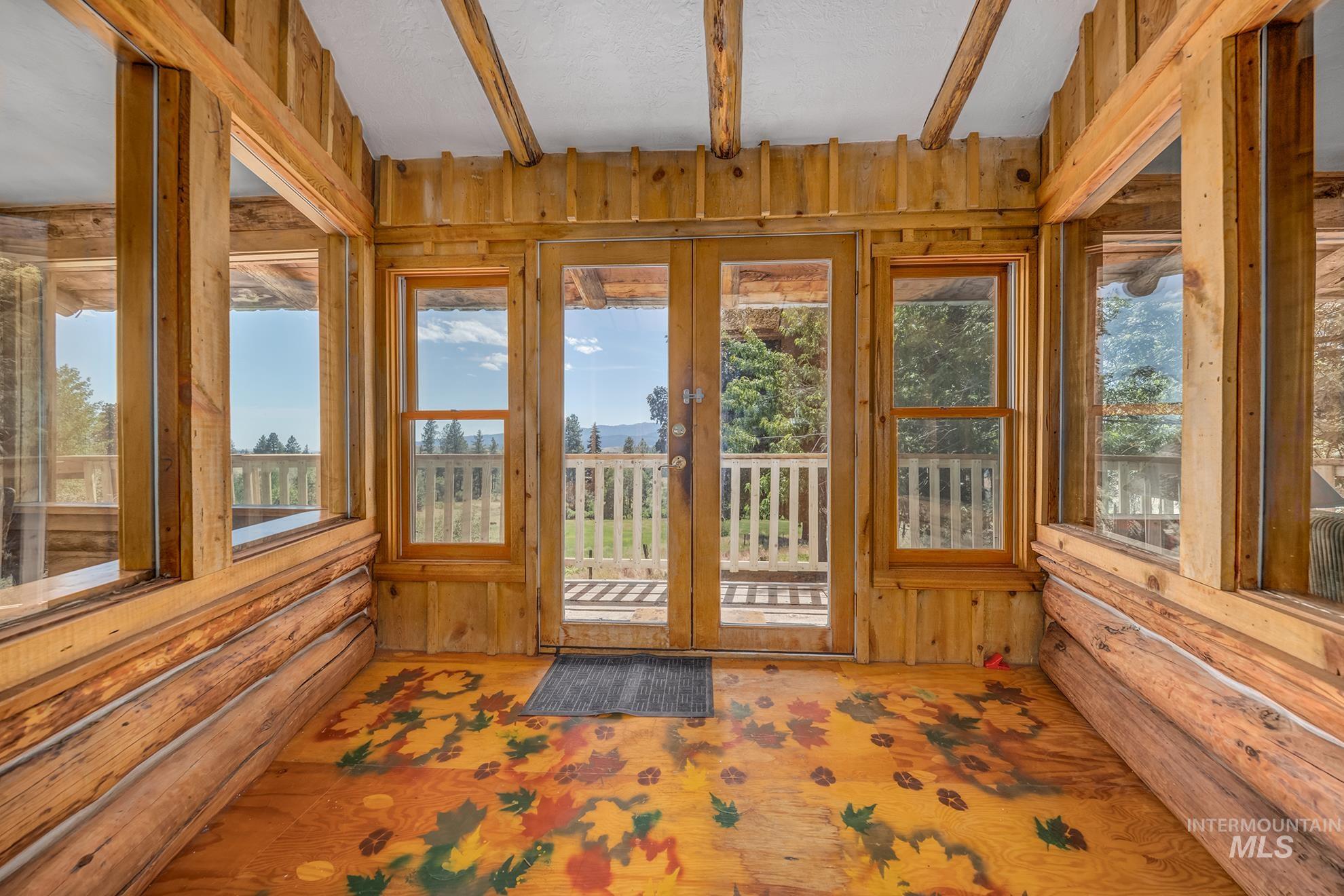 2150 Seid Creek Road Cambridge, ID 83610 - Photo 13 of 50 Sunroom featuring natural wood-finish plank and log walls, exposed beam ceiling, and multiple windows