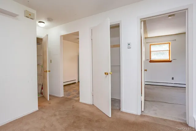 a view of an empty room with closet and a bathroom