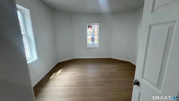 a view of empty room with wooden floor and fan