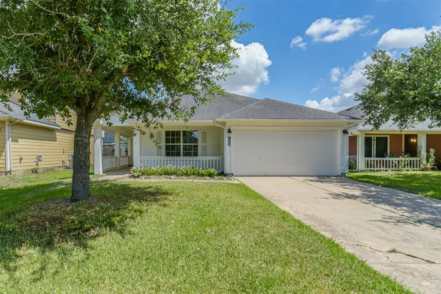 a view of a yard in front of a house with plants and large tree