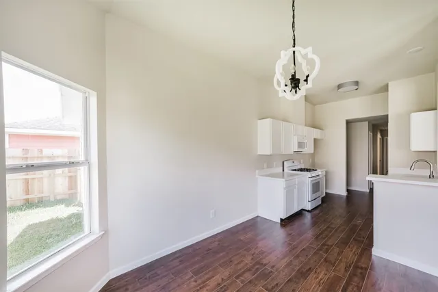 a view of a kitchen with a stove wooden floor a sink and a window